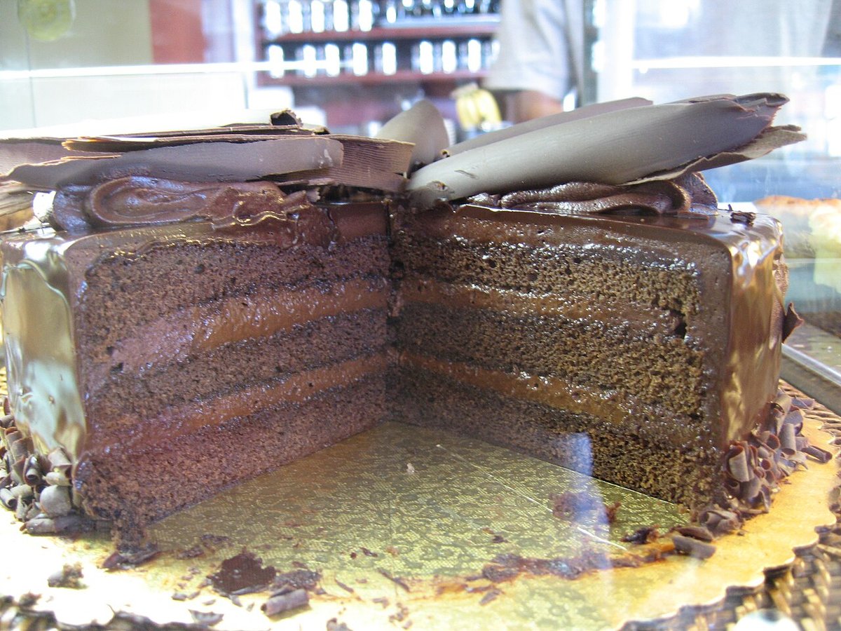 Bolo de chocolate em camadas com cobertura cremosa e lascas de chocolate