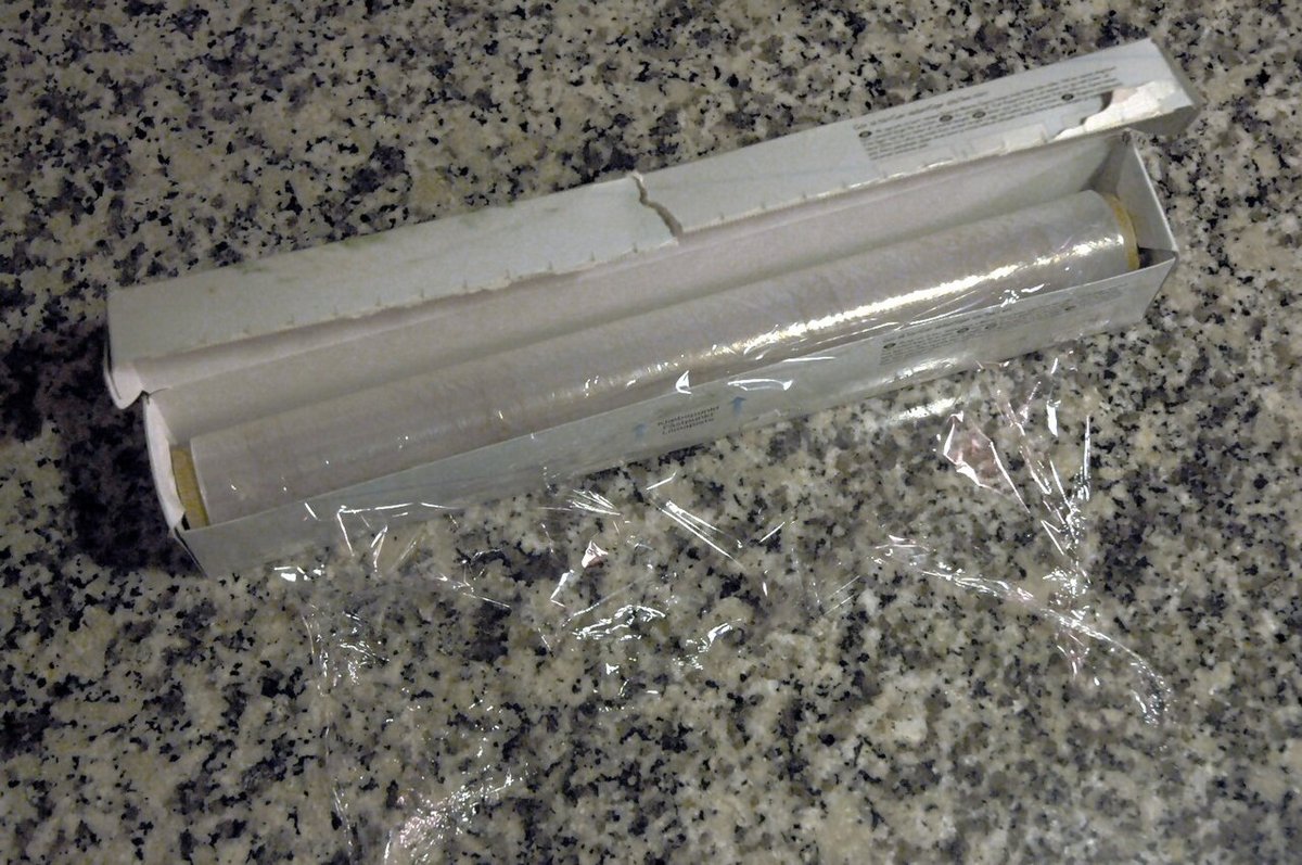 Rolo de filme plástico de cozinha aberto sobre bancada de granito