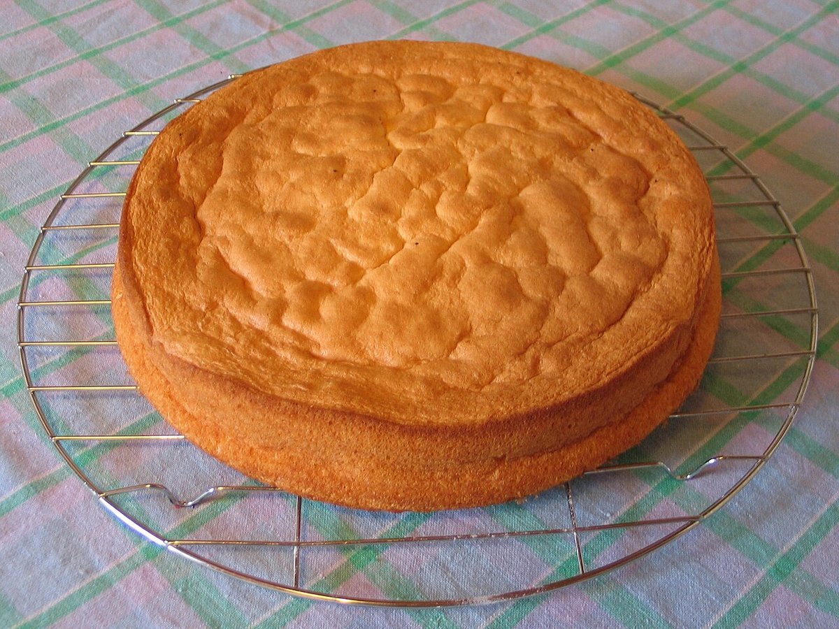 Pão de ló dourado e alto esfriando sobre uma grade redonda