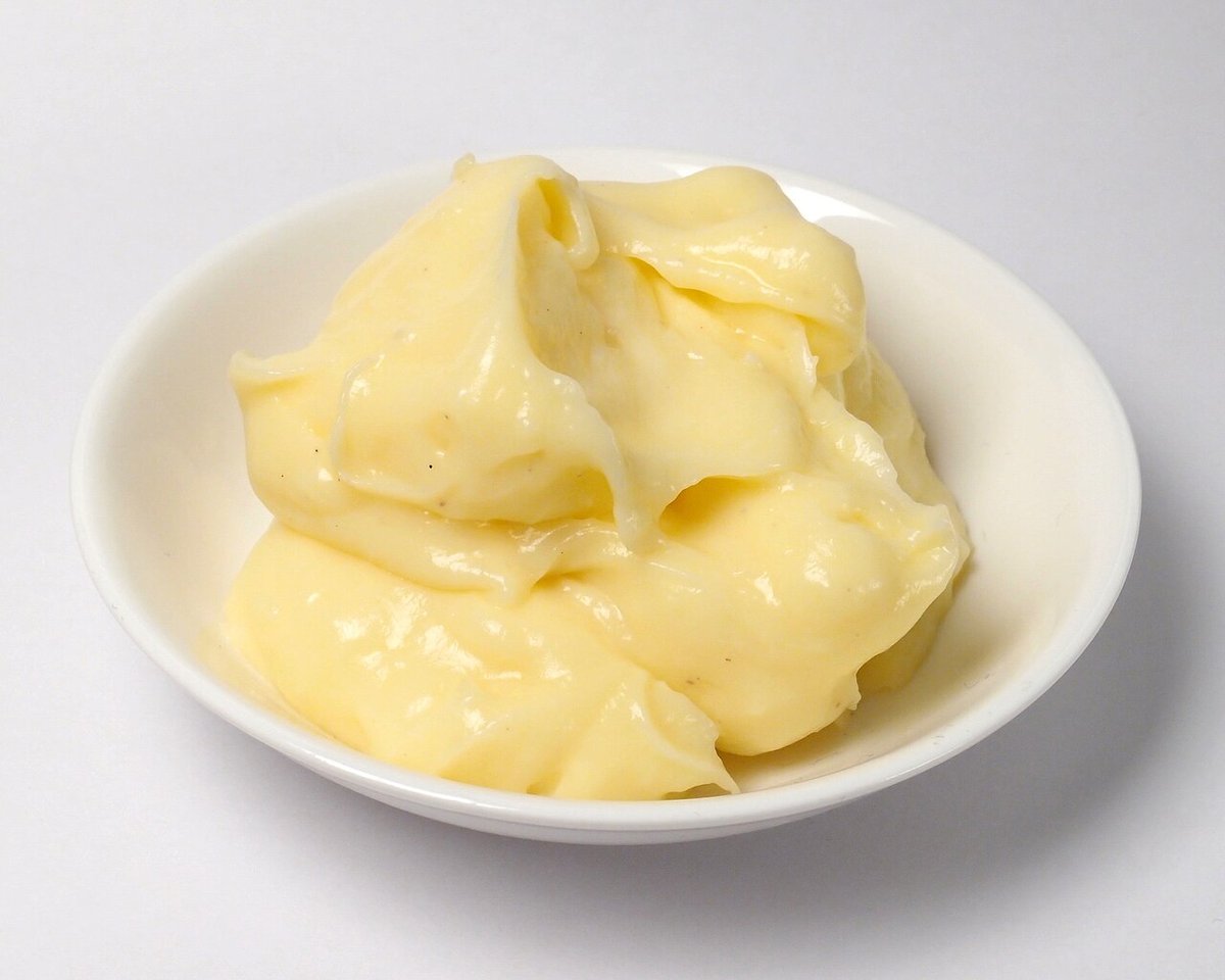 Creme de confeiteiro amarelo e liso servido em uma tigela branca