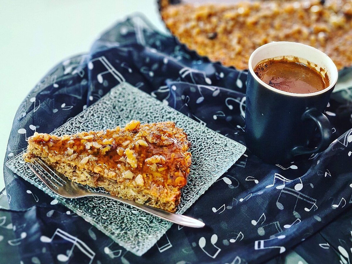 Fatia de bolo com cobertura crocante de nozes servida com café