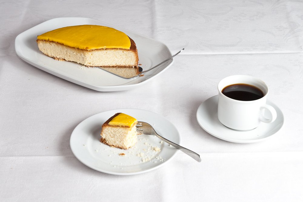 Bolo claro e leve com cobertura amarela, fatia servida com xícara de café