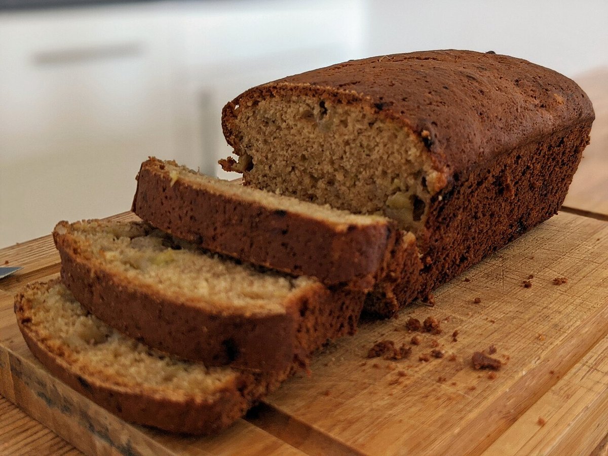 Bolo de banana em formato de pão cortado em fatias sobre tábua de madeira