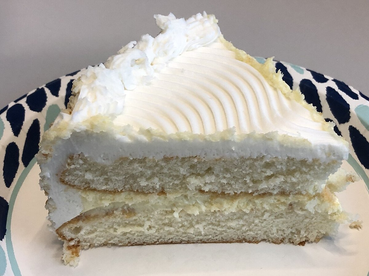 Fatia de bolo branco de baunilha em camadas com cobertura de creme