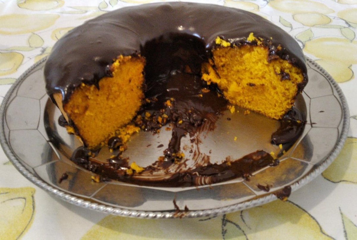 Bolo de cenoura alaranjado com cobertura de chocolate, cortado em pedaços