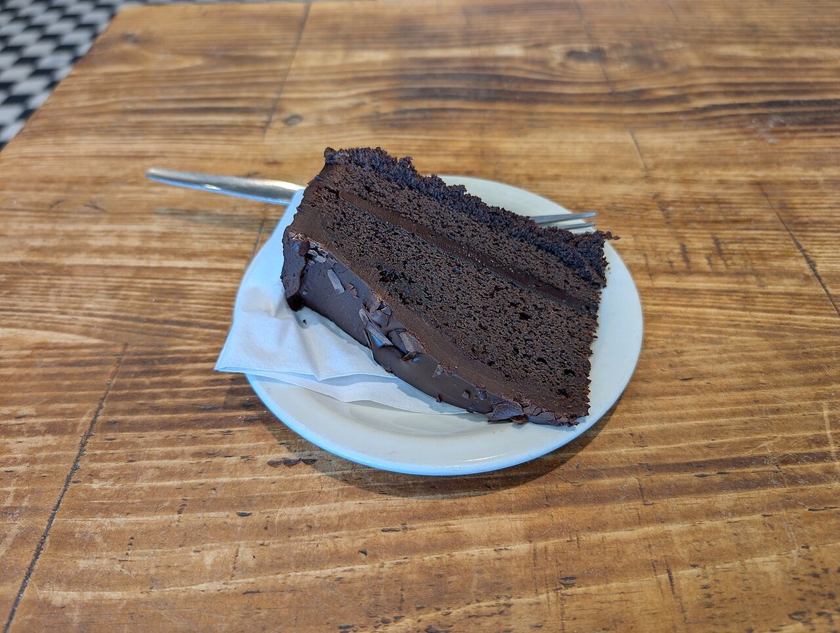 Fatia de bolo de chocolate escuro e úmido recheado com ganache em prato