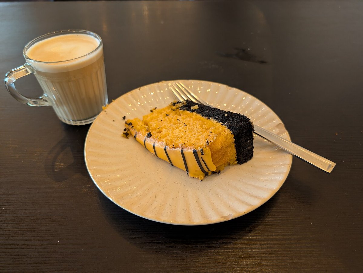 Fatia de bolo de laranja e chocolate servida com café com leite