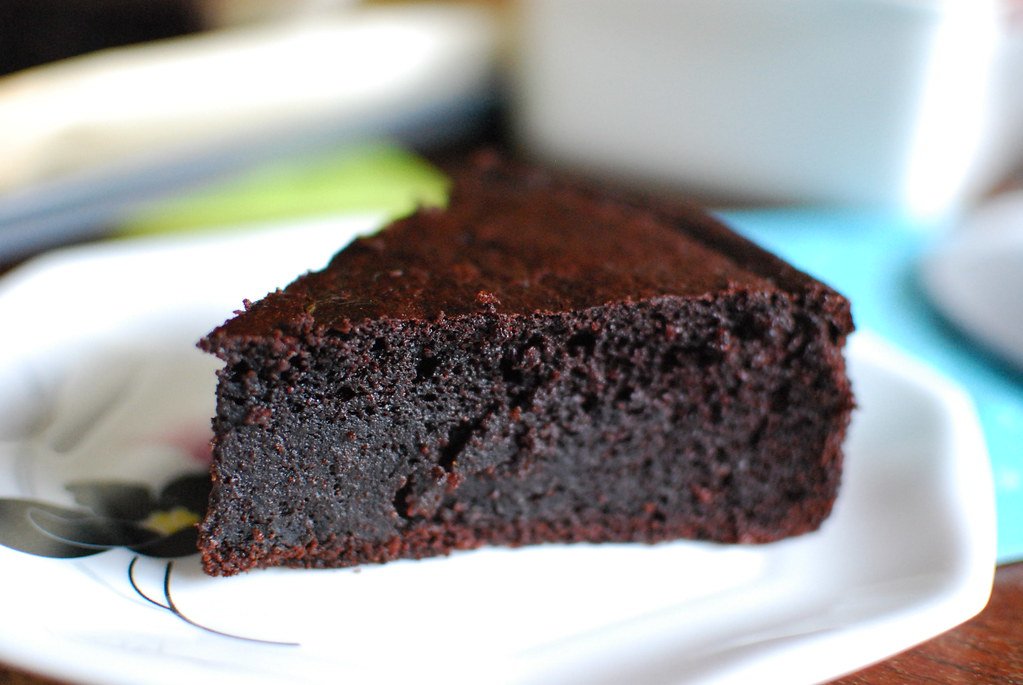 Fatia de bolo de chocolate escuro e úmido servida em prato branco