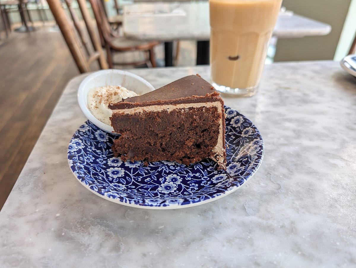 Fatia de bolo de chocolate denso com cobertura de chocolate em prato azul