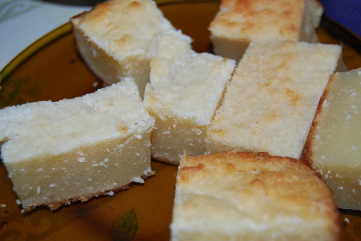 Pedaços quadrados de bolo de coco branco e úmido servidos em prato