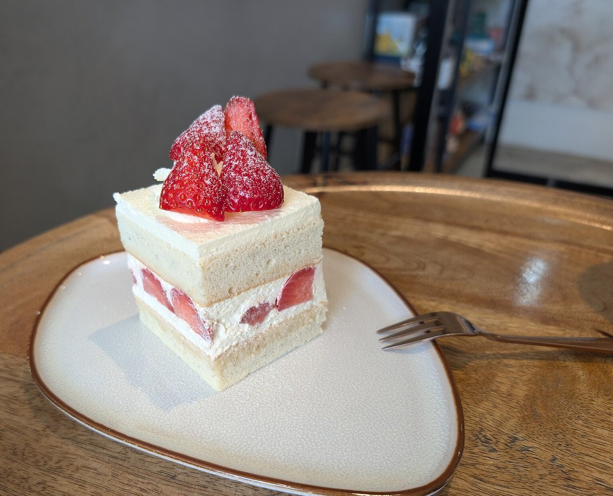 Fatia de bolo branco recheado com creme e morangos, decorada com morangos