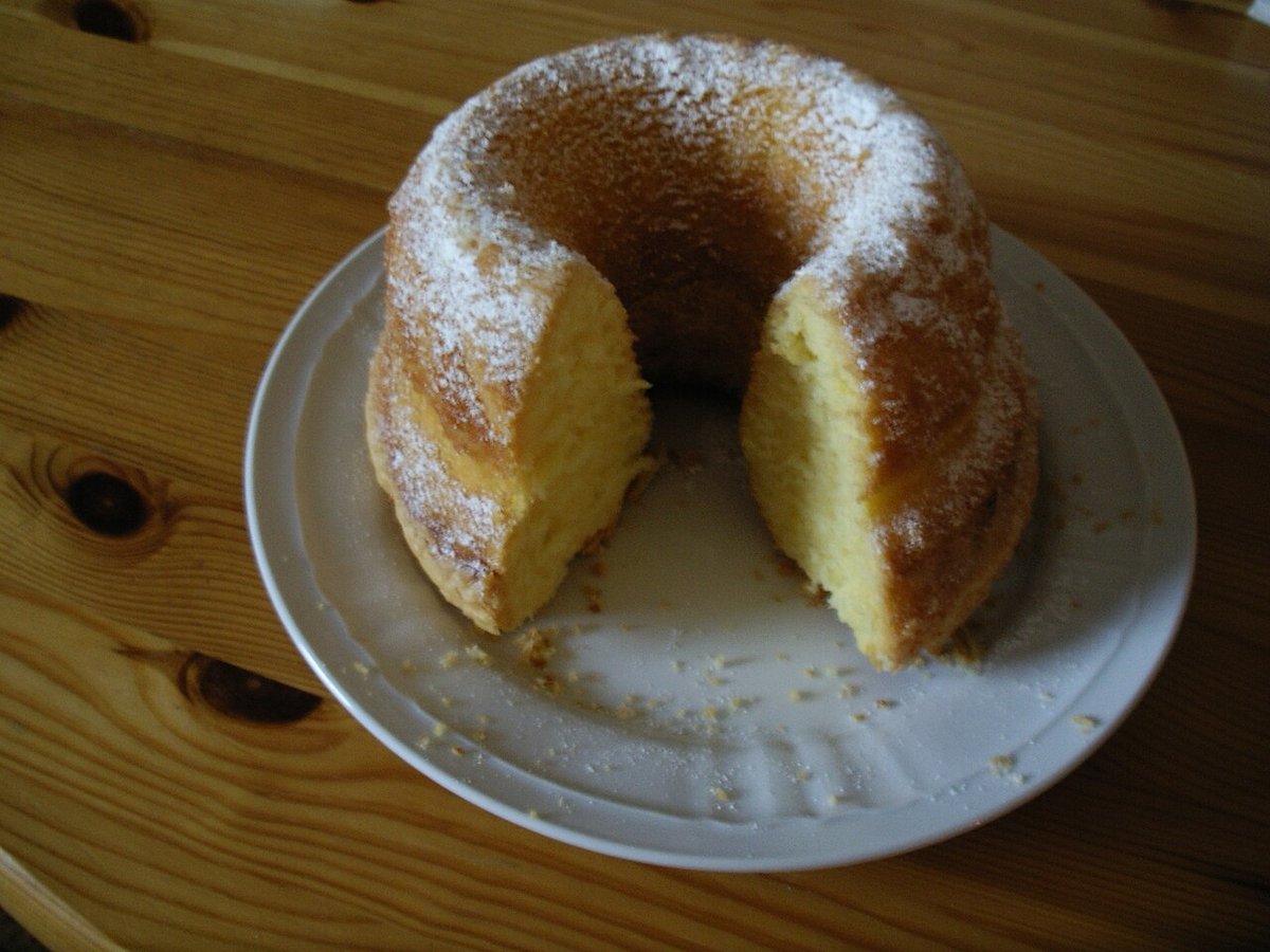 Bolo amarelo fofinho em forma de anel, polvilhado com açúcar e cortado