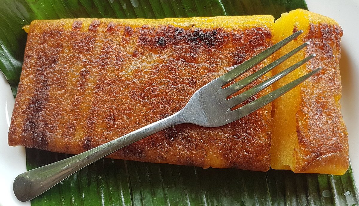 Pedaço de bolo de mandioca com casquinha tostada sobre folha de bananeira