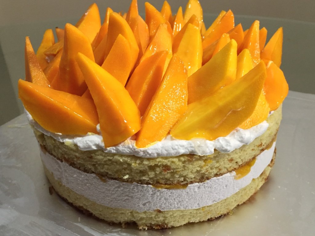 Bolo em camadas com creme branco e fatias de manga madura por cima