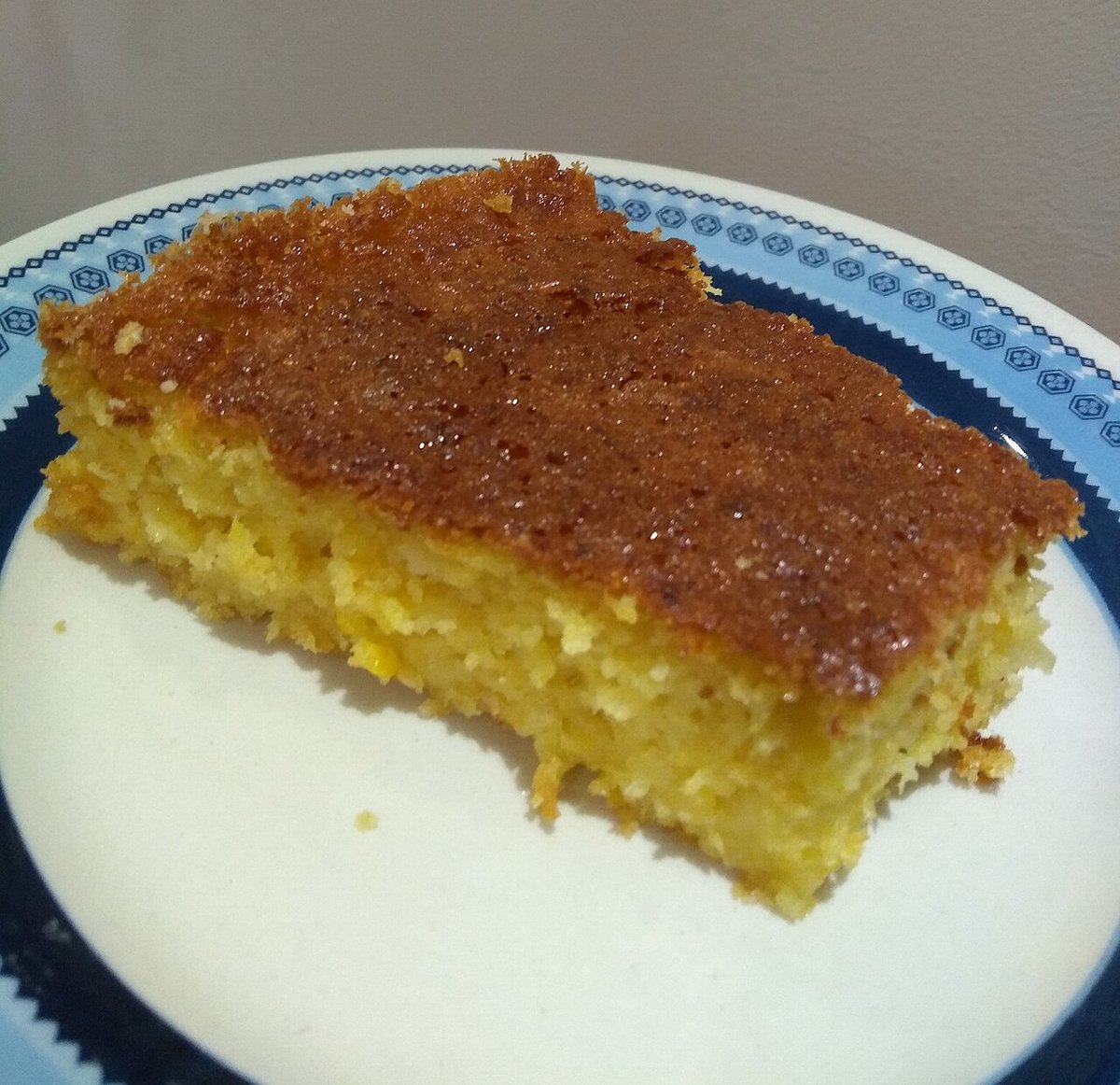 Pedaço de bolo de milho úmido e dourado em prato azul e branco
