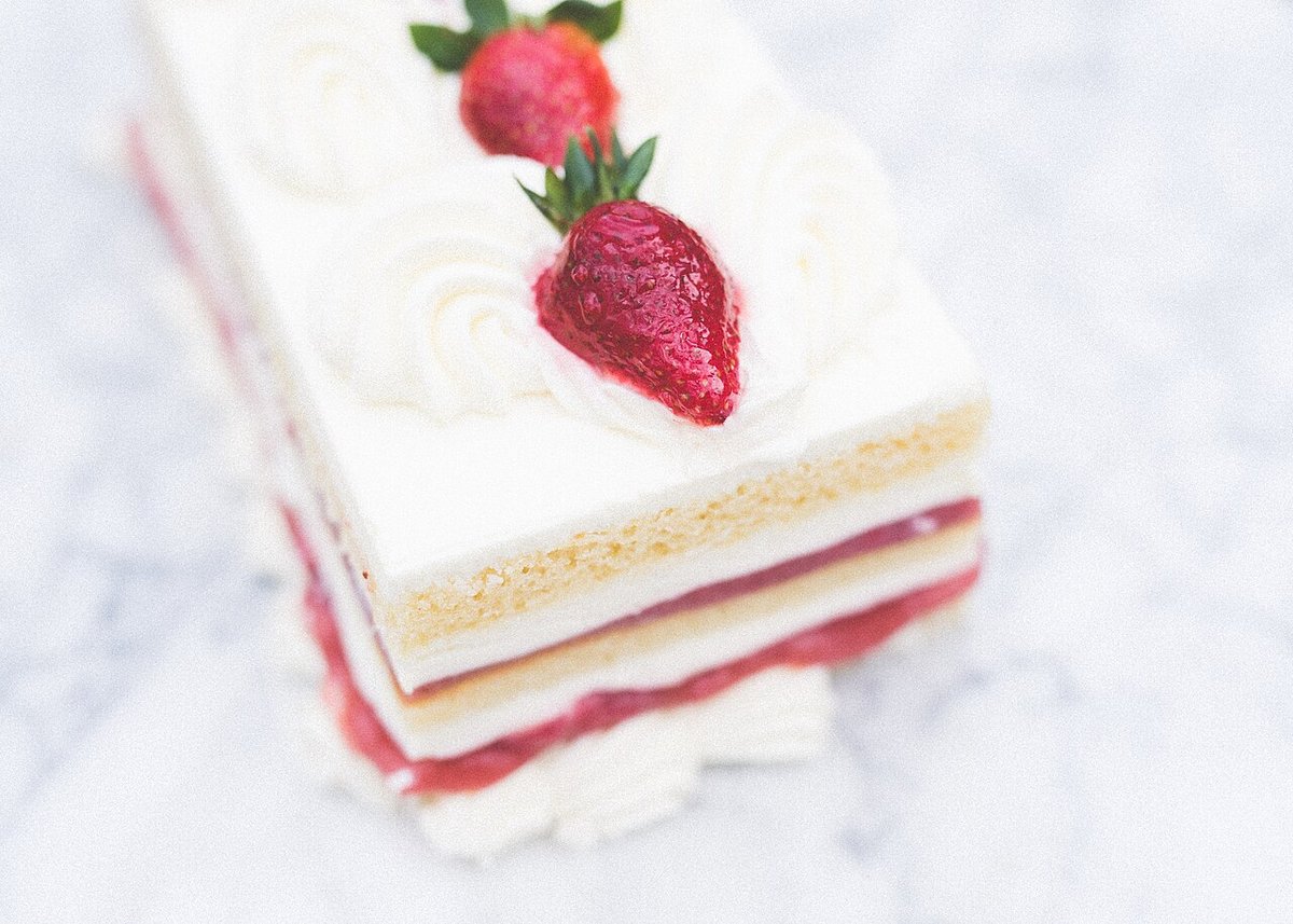 Pedaço de bolo em camadas com chantilly, recheio de morango e morangos frescos
