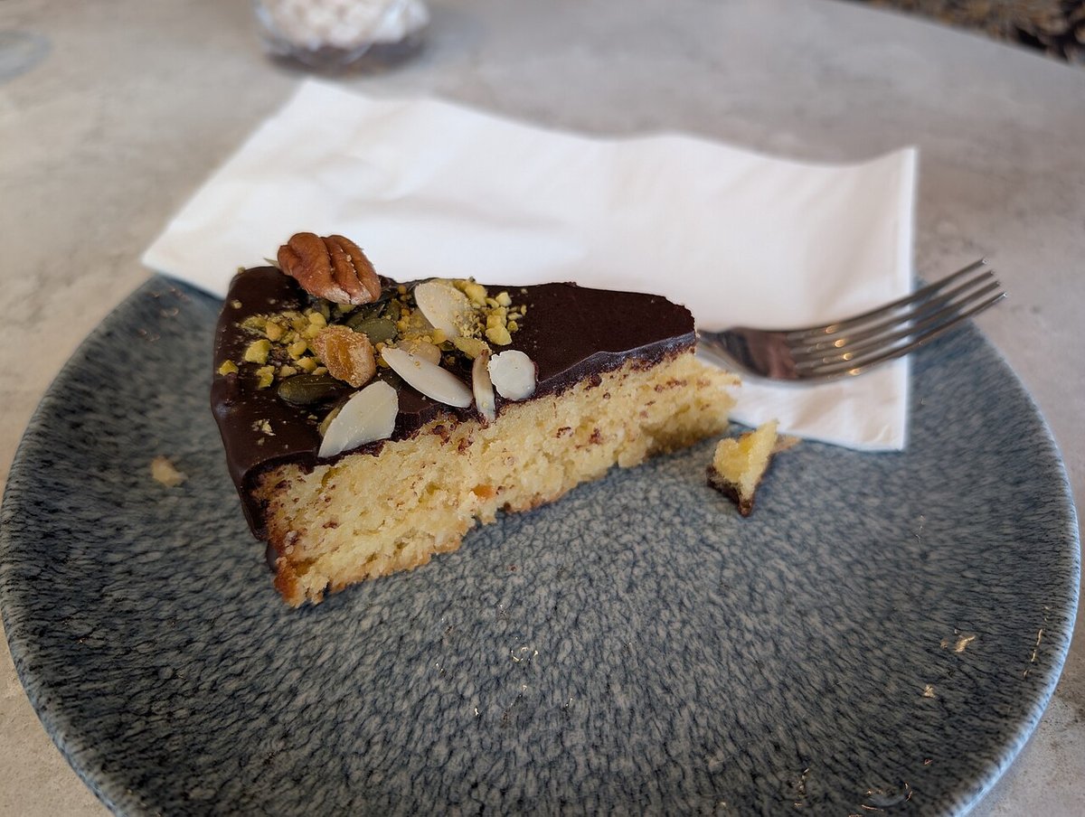 Fatia de bolo de coco com cobertura de chocolate e castanhas por cima